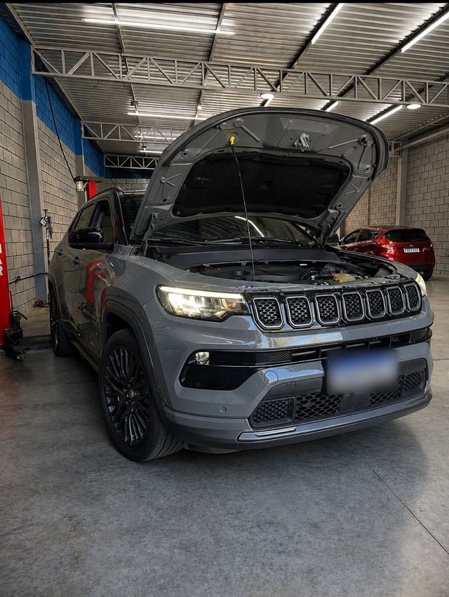 Jeep Compass cinza com capô aberto e faróis acesos para diagnóstico