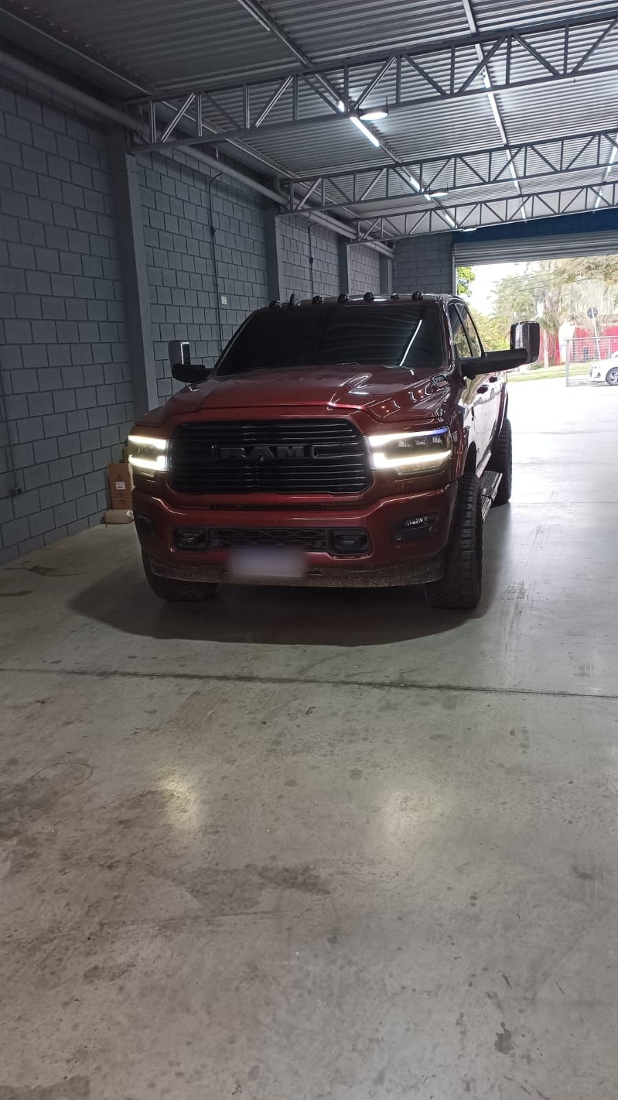 Ram 2500 vermelha com faróis de LED acesos dentro da oficina